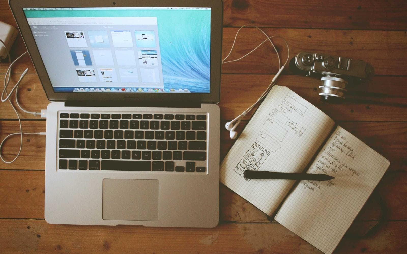 Open laptop next to a notebook with sketches