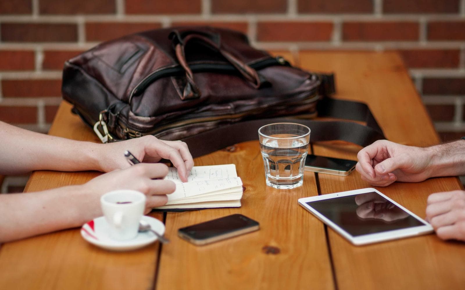 Two people writing notes at a table with coffee