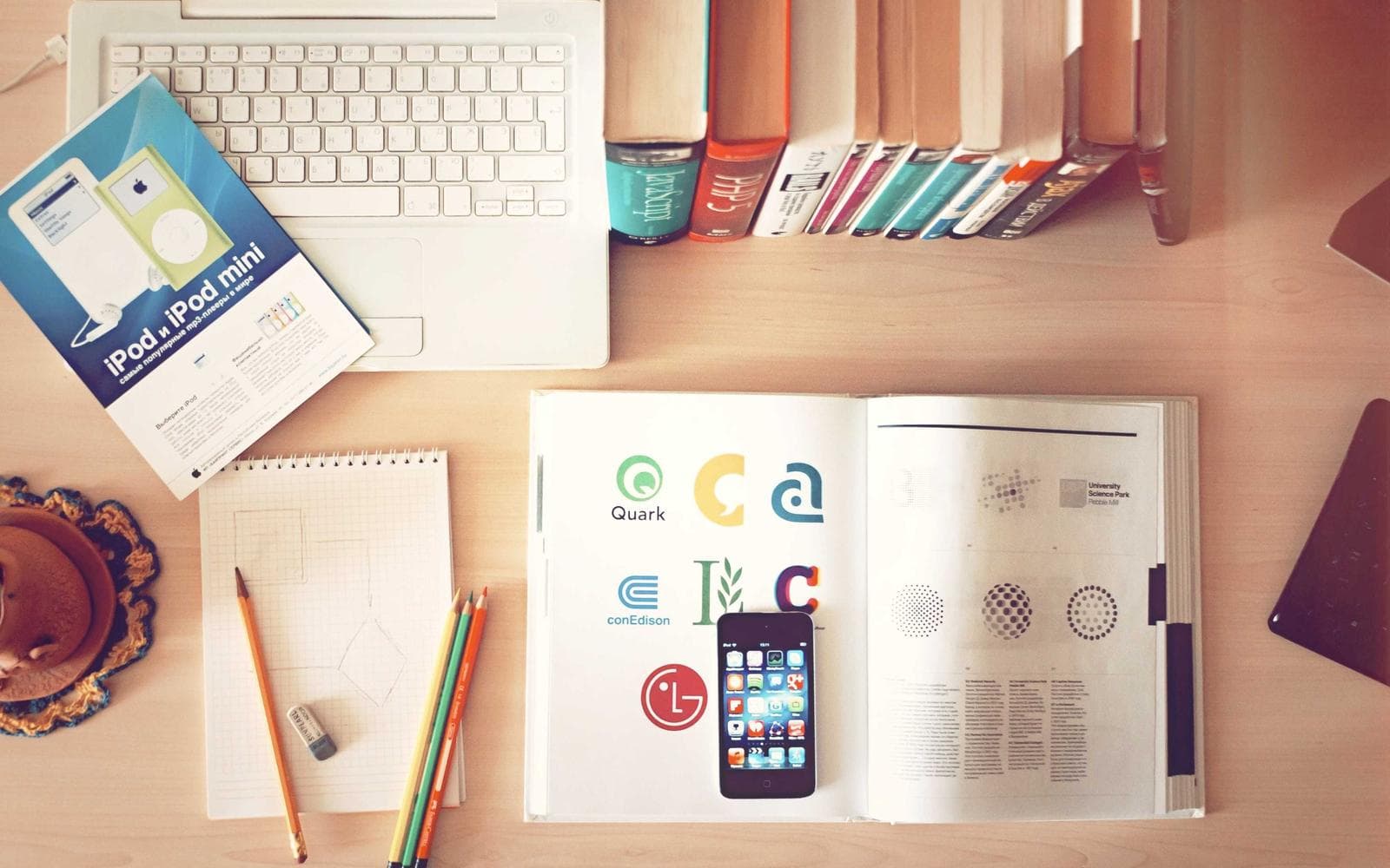 Desk covered in design books, sketches, and a phone